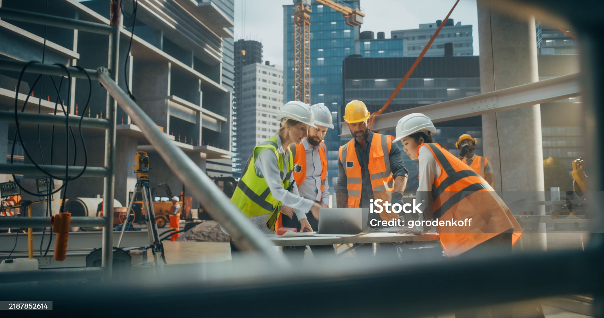 Female Civil Engineer Using a Laptop Computer and Talking with General Workers at a Residential Building Construction Area. Female and Male Employees Oversee the Real Estate Project Plan